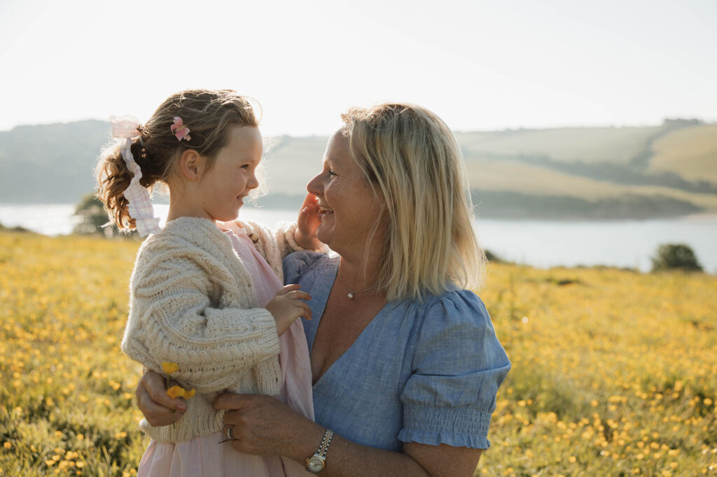 portrait of a mother and daughter tenderly laughing together in a buttercup field
