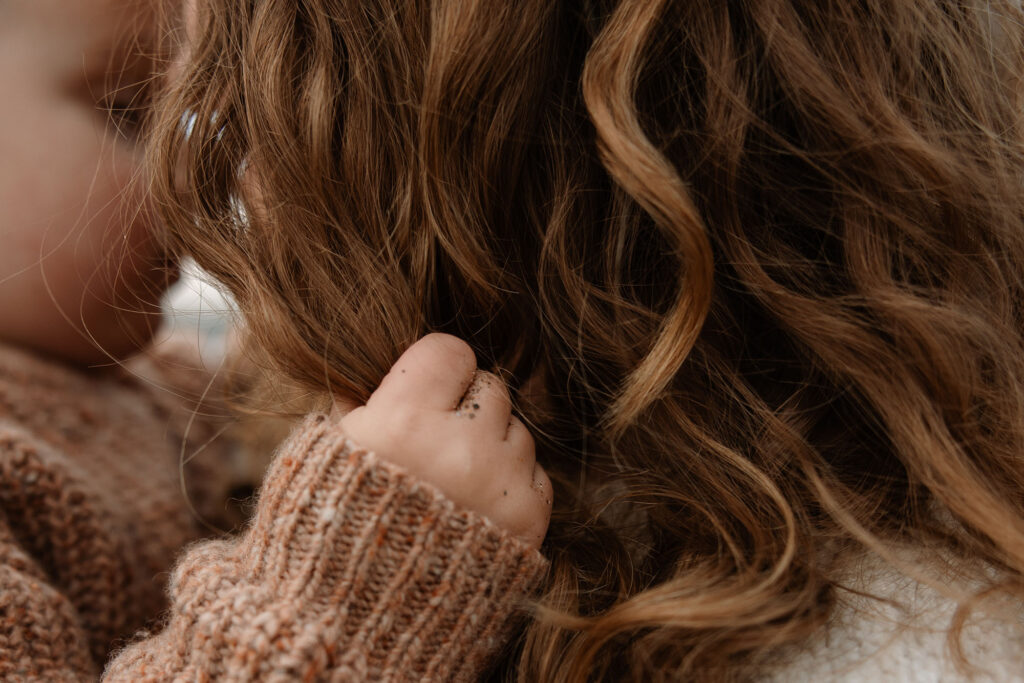 photo of a small child's hand in his mother's hair