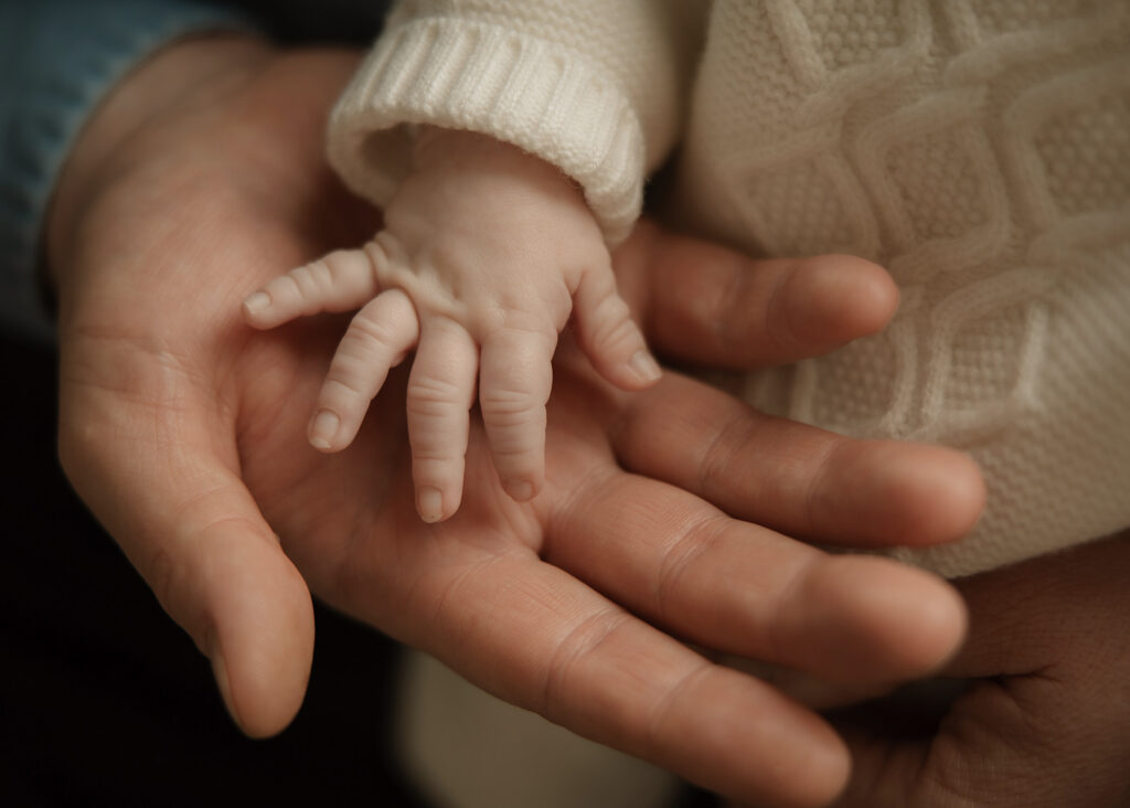 newborn baby's tiny hand cradled by father's large hand